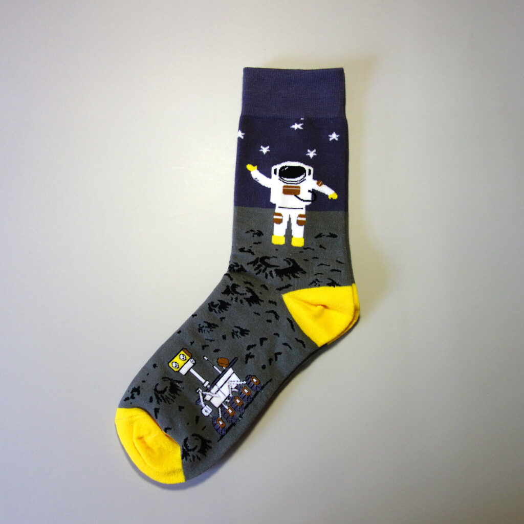 A pair of custom sock with astronaut and a research robot on mars, you can also see stars shining. Custom sock base color: Grey and dark. Heel & toe color: bright yellow.