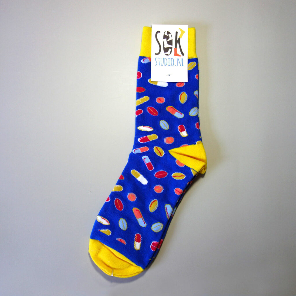 Creative custom sock design with many pills over the sock tube. Attached is the custom made top tag. Base color: dark blue, secondary colors: yellow, red, light blue, white, etc